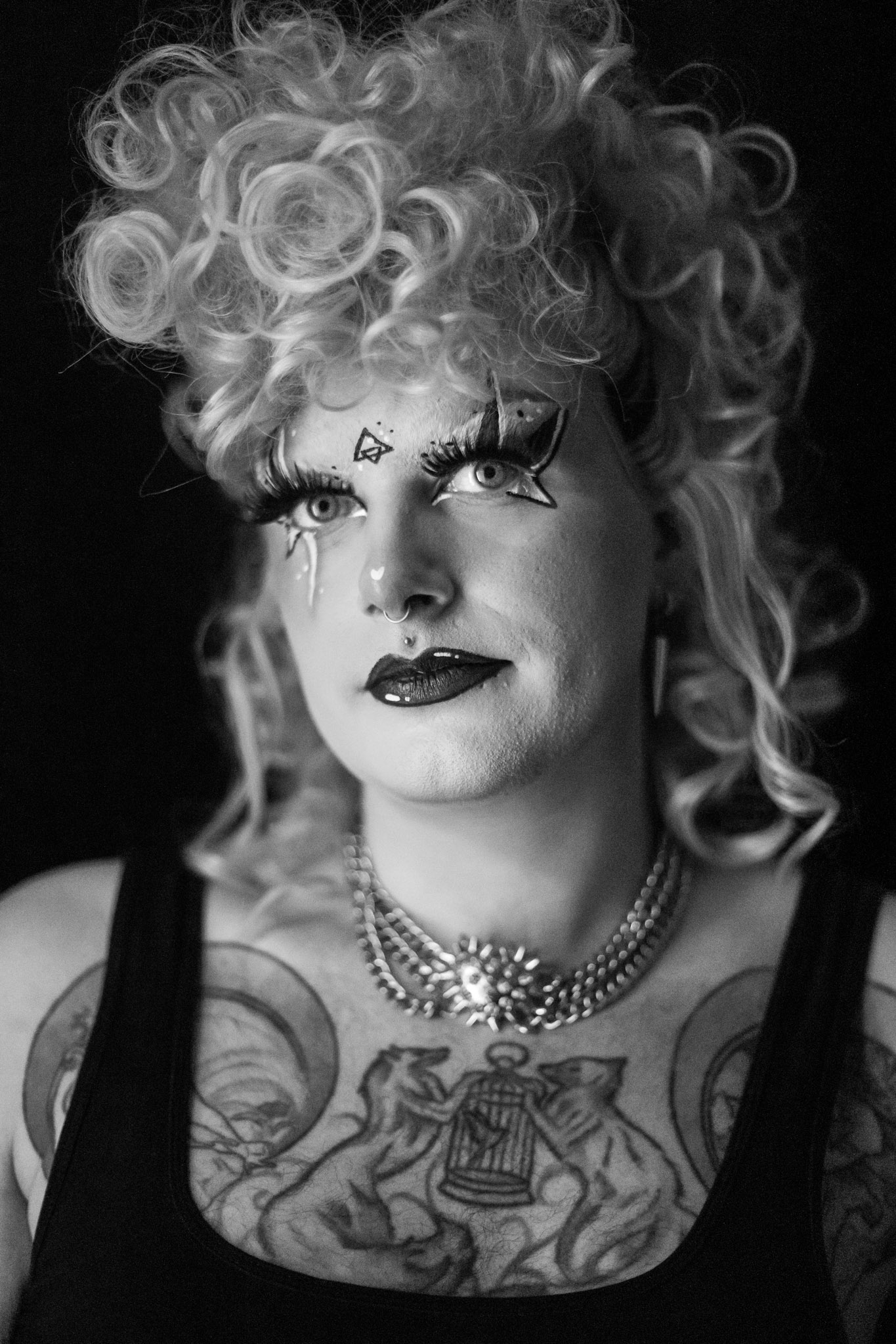 Drag-Person mit Locken, Stern auf der Stirn und Tattoos im Porträt